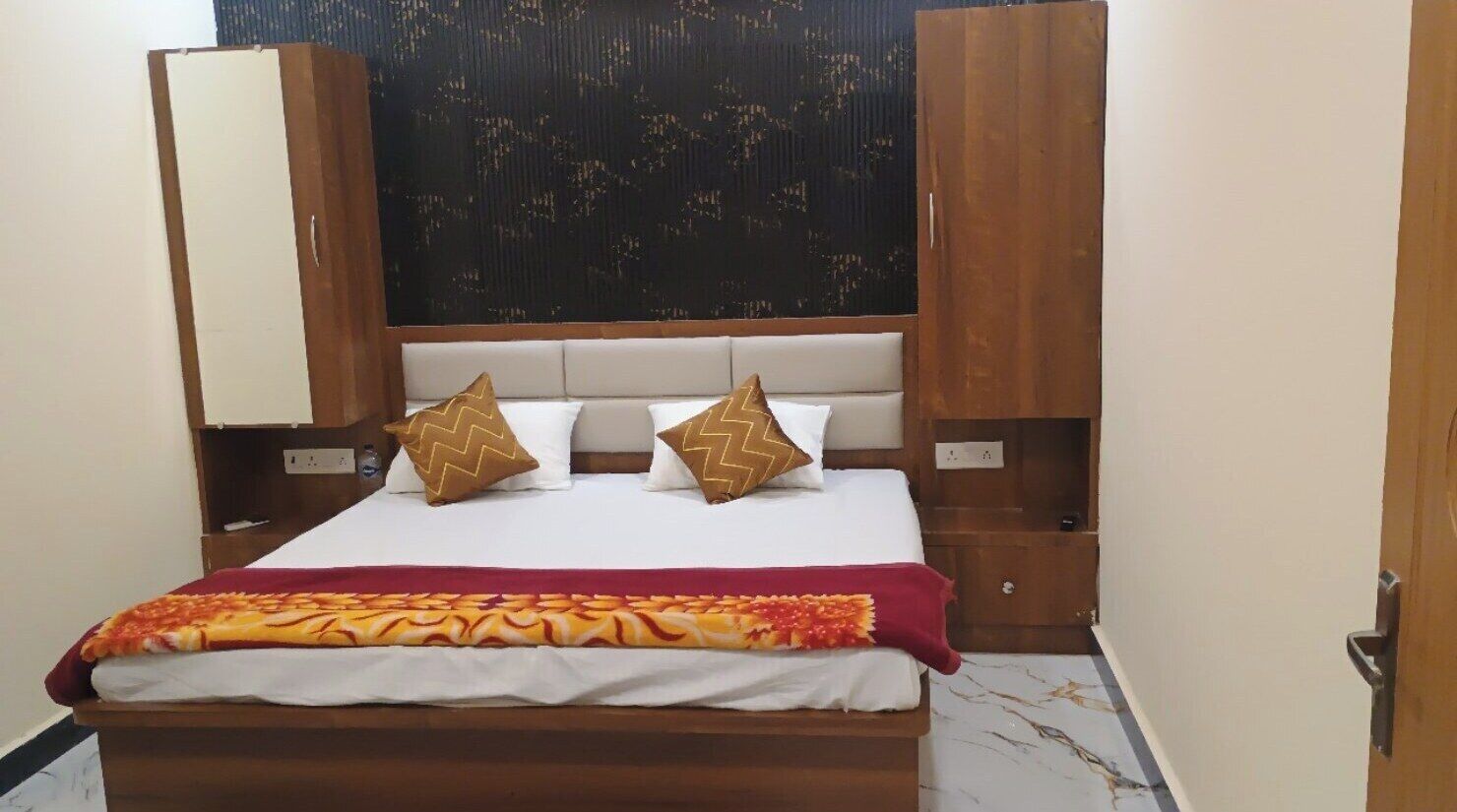 A bedroom with a bed, two nightstands, a wardrobe, and a patterned wall.