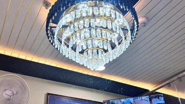 Un lustre, un ventilateur fixé au mur et un écran numérique doté de plusieurs affichages.