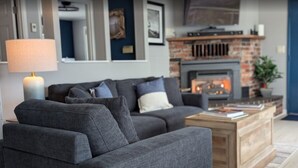 Ein modernes Wohnzimmer mit grauem Sofa, einem Holztisch und einem Kamin.