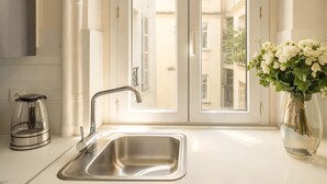 A kitchen with a stainless steel sink, a kettle, and a vase with flowers. - Trocadero - Elegant apartment with lift (Unknown)