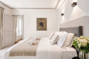 Una habitación de hotel con una cama, un cuadro y un florero con flores.
