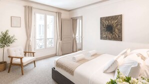 A bedroom with a bed, a chair, a potted plant, and a door leading to an outdoor balcony. - Trocadero - Elegant apartment with lift (Unknown)