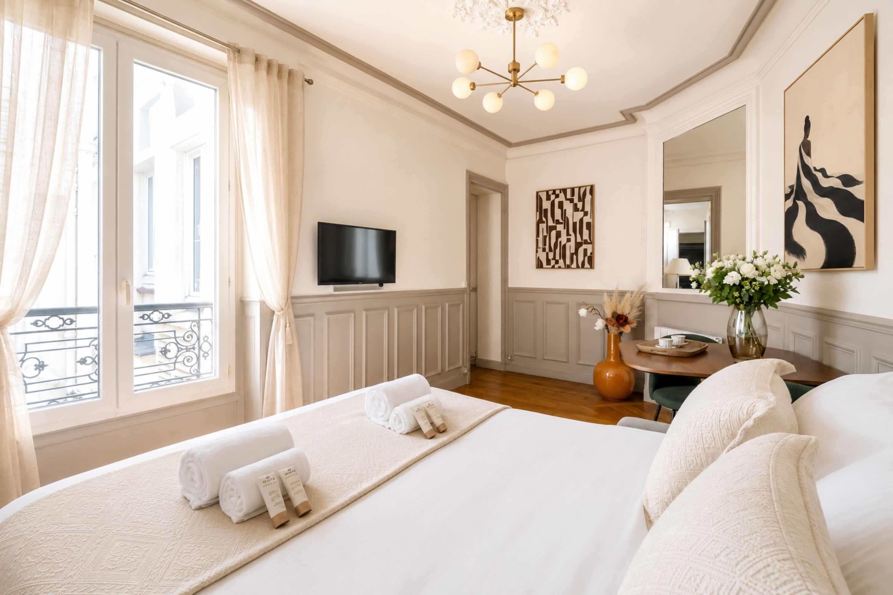 Een hotelkamer met een groot bed, een televisie, een decoratief wandobject en uitzicht op het buitenbalkon.