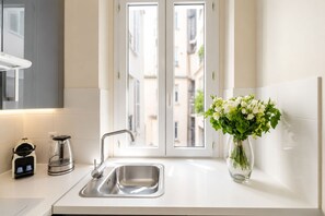 A modern kitchen with a stainless steel sink, a coffee maker, and a vase with flowers on the counter.