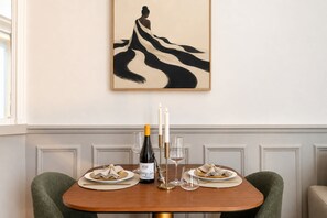A dining table with a bottle of wine, two glasses, and a candle.