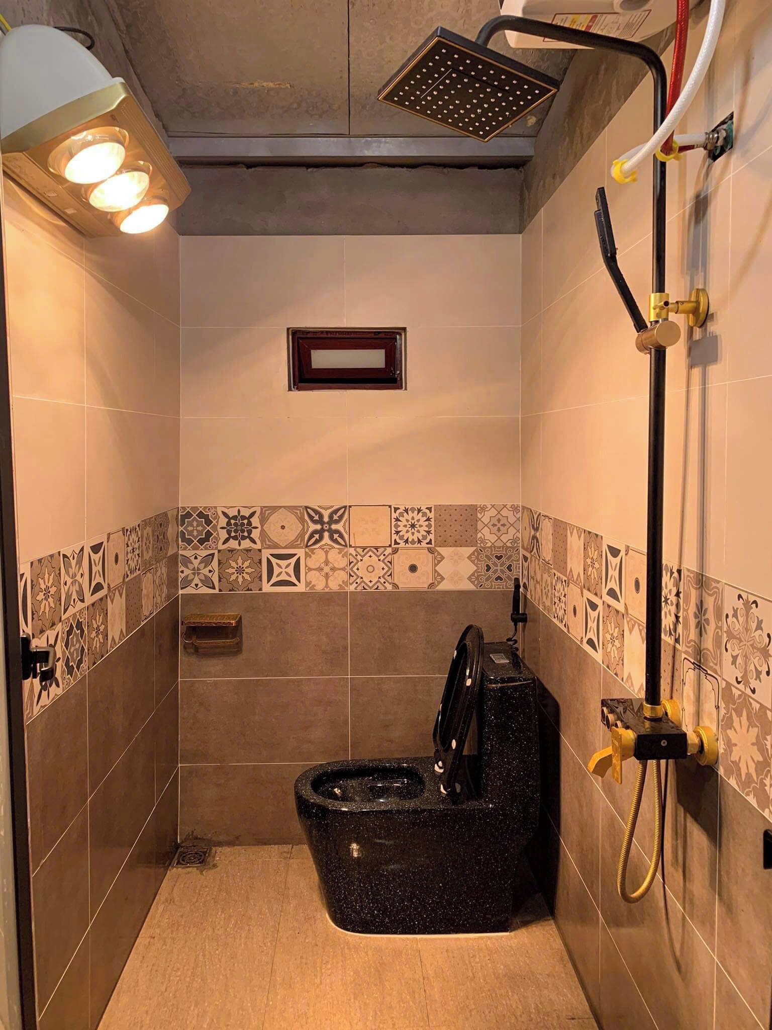 A small, tiled bathroom with a shower, a toilet, and a sink.