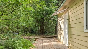 A wooden deck leading to a house surrounded by dense greenery. - Fairway Paradise | AC, Hot Tub, BBQ (Packwood)