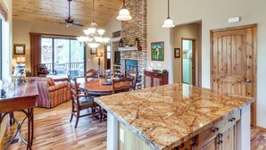 A spacious kitchen with a large granite island, wooden ceiling, and a stone fireplace. - 4 Miles to Lake: Retreat w/ 2 Decks! (Show Low)