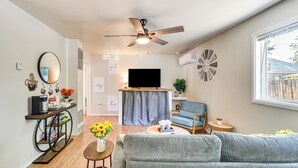 Un salon moderne avec un canapé, un téléviseur, un ventilateur de plafond et une fenêtre donnant sur un beau paysage.