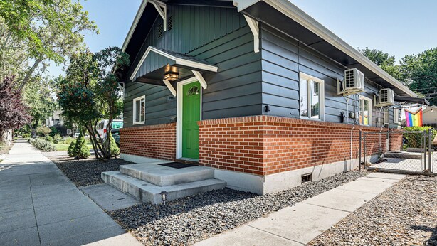 Une maison à deux étages avec une porte verte, des fondations en briques et un toit en pente.