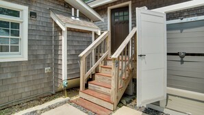 A residential house with a wooden staircase leading to a front door, a garage door, and a window with a white frame. - 1 Mi to Ferry Terminal: Oak Bluffs Family Retreat! (Oak Bluffs)