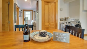 A wooden table with a bottle of wine, a decorative plate, and a welcome sign. - 1 Mi to Ferry Terminal: Oak Bluffs Family Retreat! (Oak Bluffs)