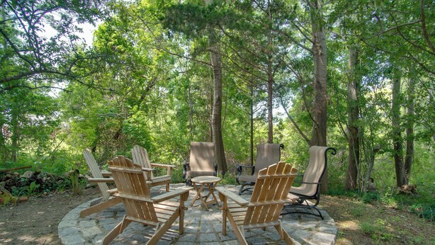 A circular stone patio with Adirondack chairs and a small table in a forested area. - 1 Mi to Ferry Terminal: Oak Bluffs Family Retreat! (Oak Bluffs)