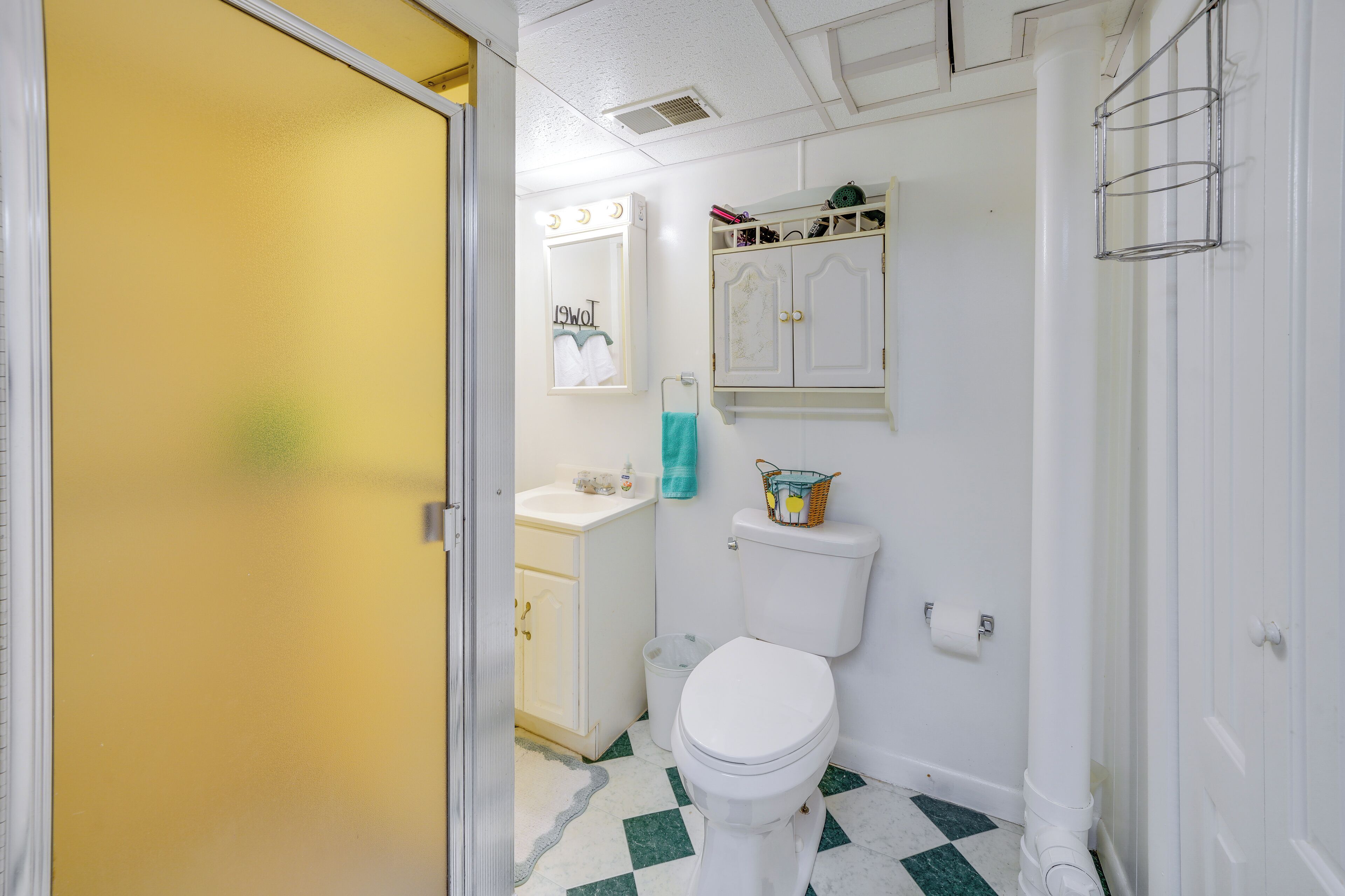 Un baño con inodoro blanco, lavamanos, espejo y armario.