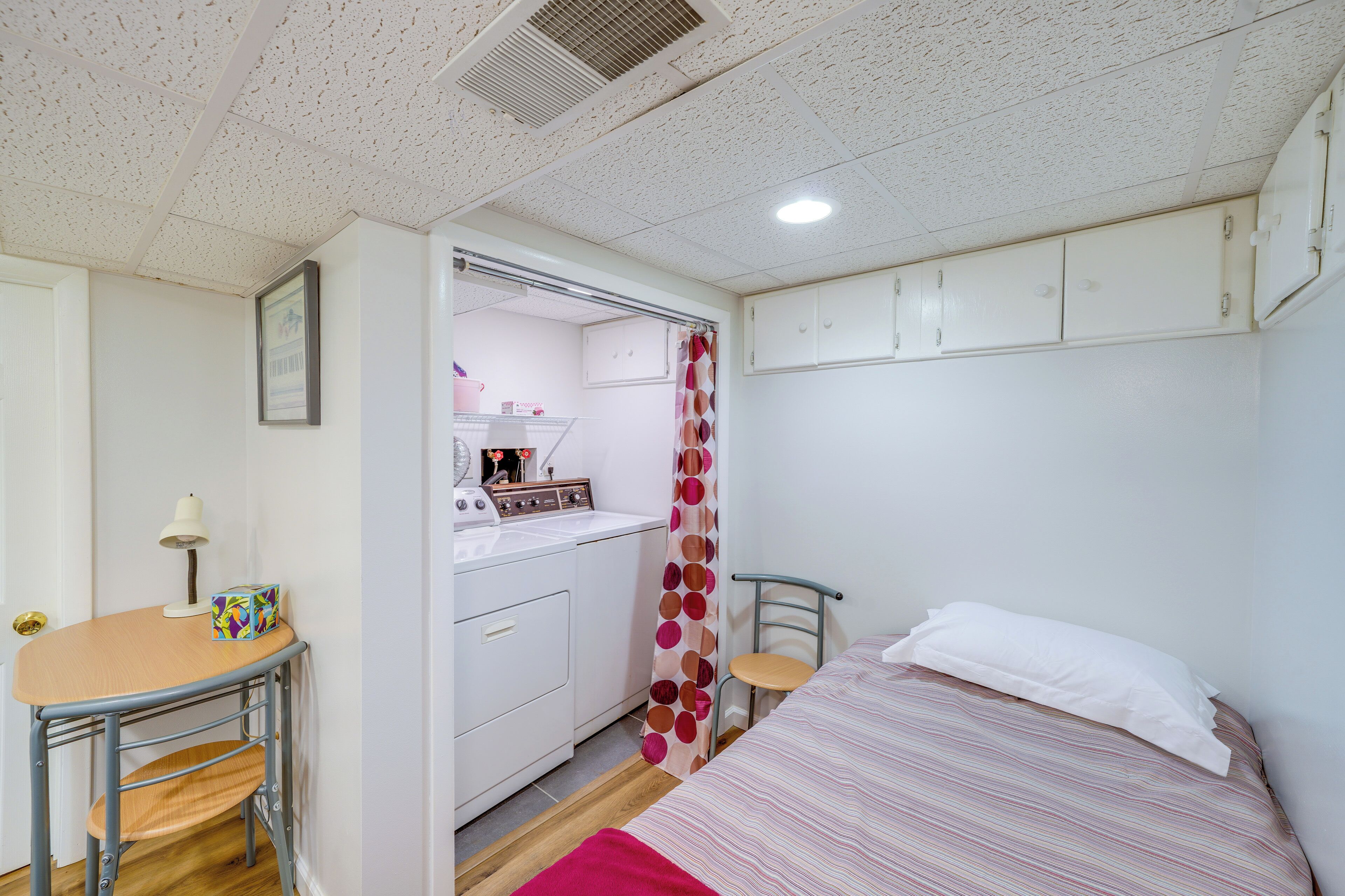 A compact bedroom with a bed, a small desk, and a kitchenette.