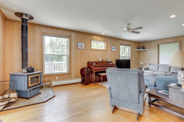 A living room with a wood-burning stove, a piano, a sofa, and a television.