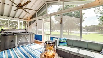 Un espace extérieur abrité comprenant un barbecue, un foyer et un coin salon offrant une vue sur l’extérieur.