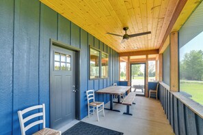 Un patio couvert doté d’un plafond en bois, de murs bleus et d’une table en bois avec des chaises.