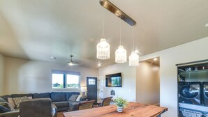 A spacious living area with a wooden dining table, a sofa, and a coffee table. There are hanging pendant lights above the table. - Missouri River Retreat < 1 Mi to the Water! (Pierre)