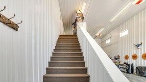 A staircase with carpeted steps leading upwards, flanked by white walls and a metal railing. - Missouri River Retreat < 1 Mi to the Water! (Pierre)