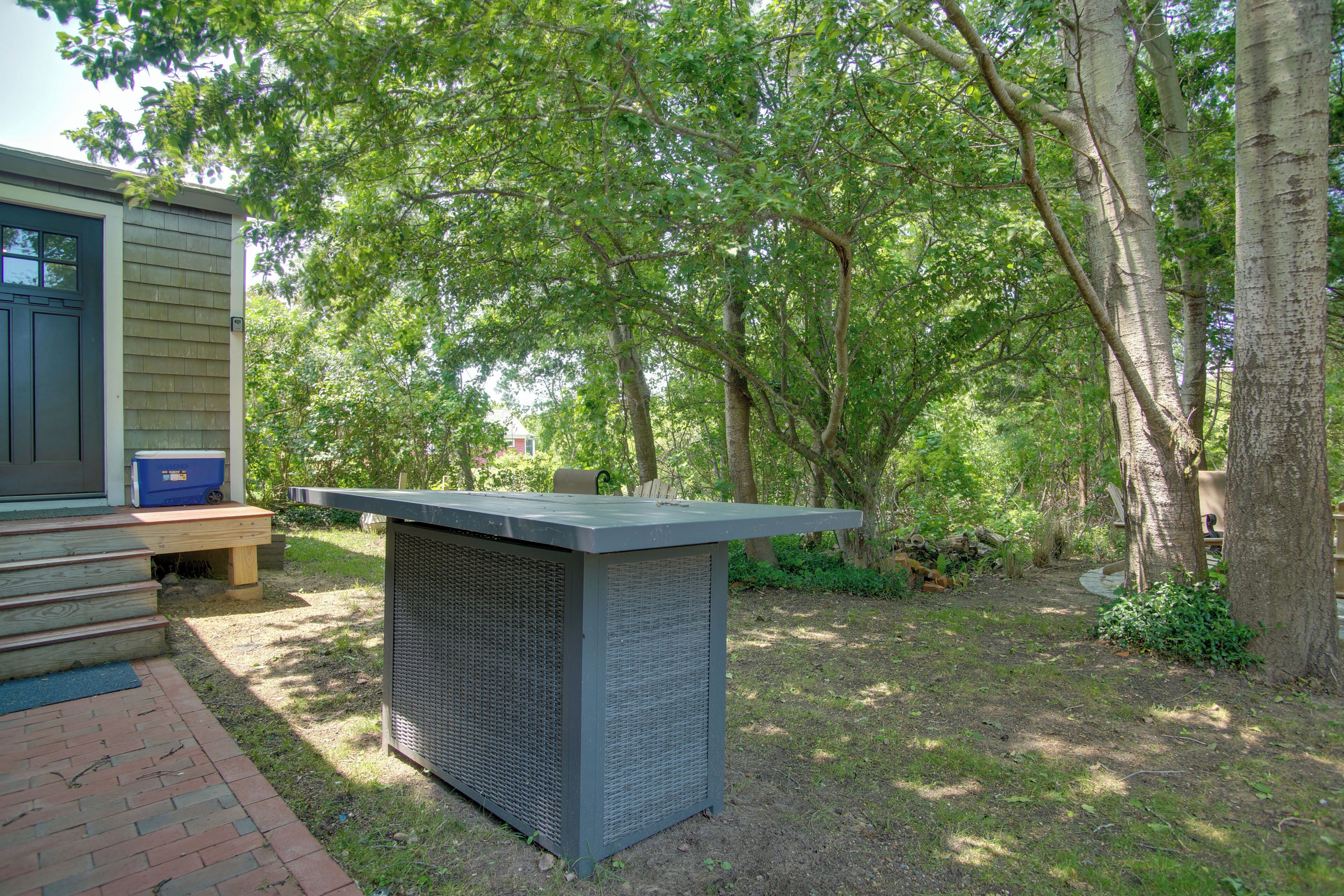 A patio area with a built-in grill and a small wooden bench.