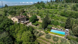 Una villa con piscina rodeada de vegetación exuberante y altos árboles.