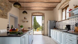 Una cocina con alacenas azul claro, una isla central con alimentos, un refrigerador y vista al exterior a través de un arco.