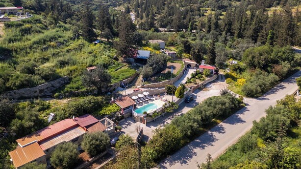 A resort with a swimming pool, a red-roofed building, and a road. - Villa Nikolas - House with pool near Almyrida in Crete (Vámos)
