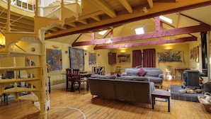 Amplia sala de estar con pisos de madera, una escalera y una mesa de comedor.