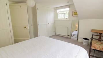 A bedroom with a bed, a window with a view, a radiator, and a chair.