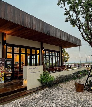 Un café moderne doté d’une terrasse, d’une façade en bois et offrant une vue sur la plage.