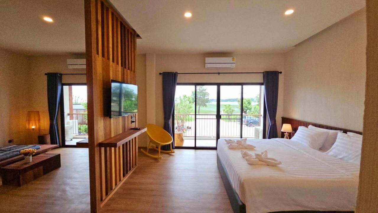 Habitación de hotel con cama, escritorio, silla, televisión y balcón con vistas.