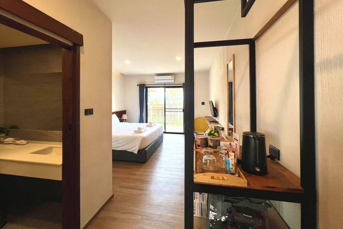 Ein Hotelzimmer mit Bett, Schreibtisch, Spiegel und einem Balkon mit Blick.