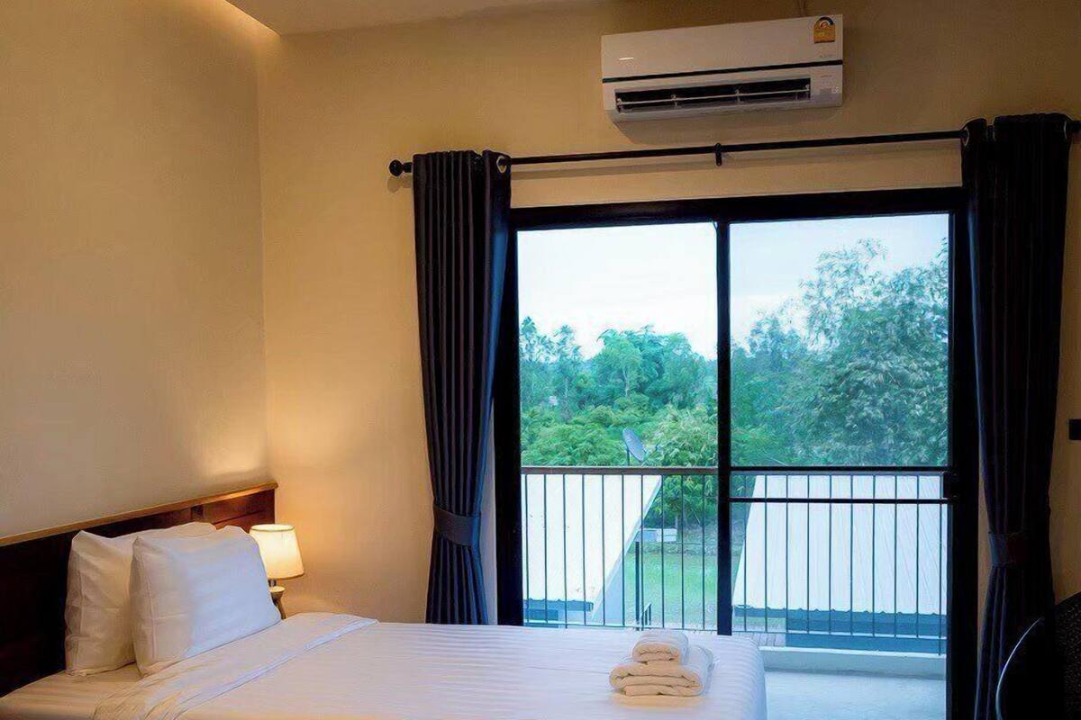 Ein Hotelzimmer mit zwei Betten, einer Klimaanlage, einem Balkon mit Blick und einem Sessel.
