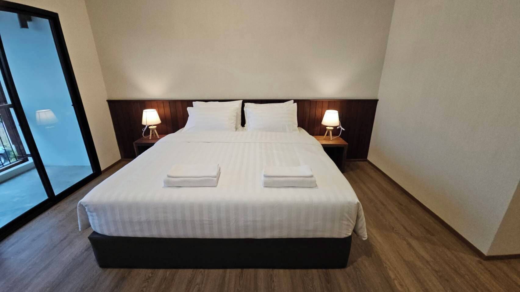 Habitación de hotel con una cama grande, dos lámparas de noche y vistas a través de un ventanal.