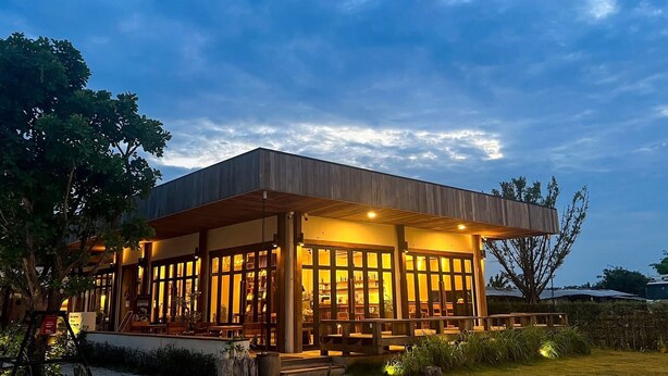 Un bâtiment moderne à l’extérieur en bois et doté de grandes fenêtres, entouré de verdure.