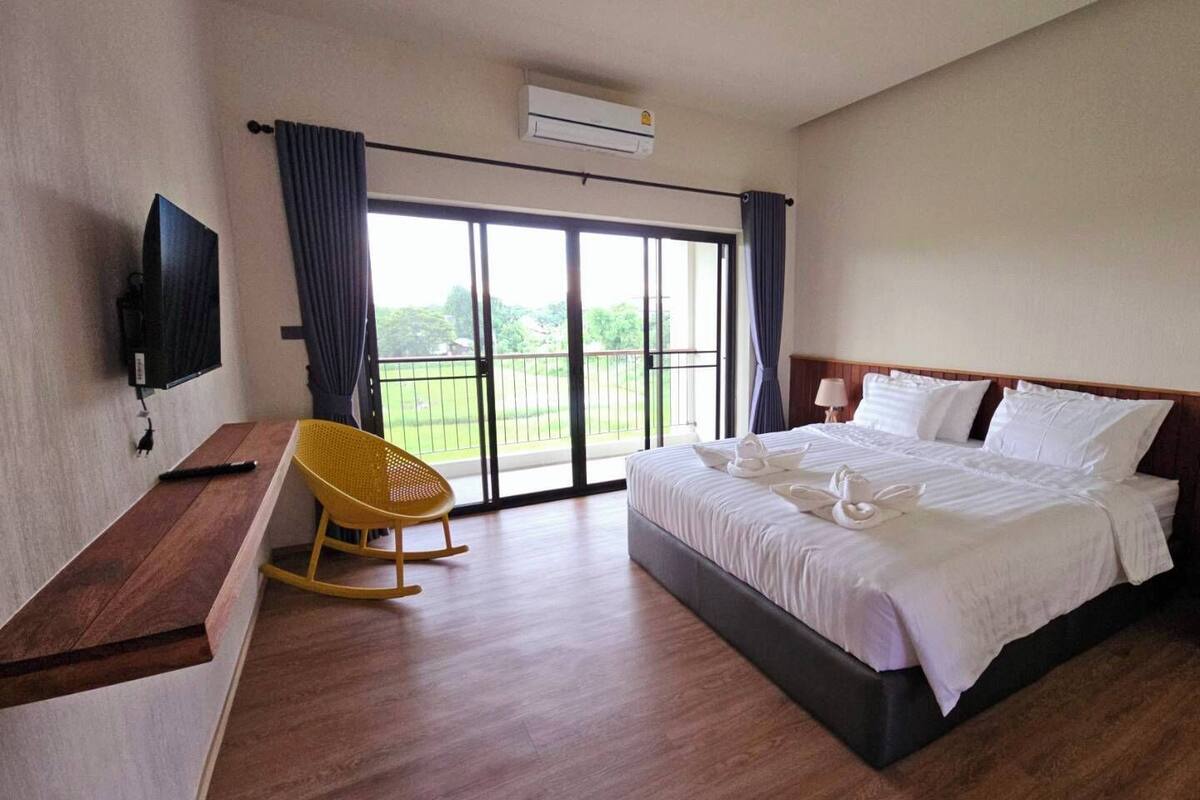 Ein Hotelzimmer mit Bett, Schreibtisch, Stuhl, Fernseher und einem Fenster mit Vorhängen.
