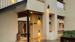 Un immeuble à plusieurs niveaux doté d’un espace extérieur couvert comprenant une terrasse en bois et un petit élément décoratif aquatique.