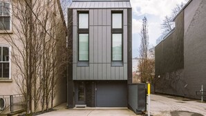 Een modern gebouw met twee verdiepingen, een plat dak, grote ramen en een garagepoort.