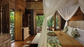 A wooden room with a bed, a bench, and a table. - Nava Prana Villa by GenuineHost (Payangan)