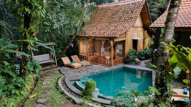 A wooden house with a tiled roof, a swimming pool, and a bench. - Nava Prana Villa by GenuineHost (Payangan)
