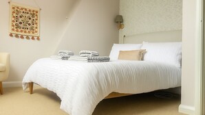 Een keurig opgemaakt slaapkamer met een bed, kussens en een wanddecoratie.