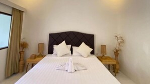Una habitación de hotel con una cama grande, dos mesitas de noche y una ventana con cortinas.