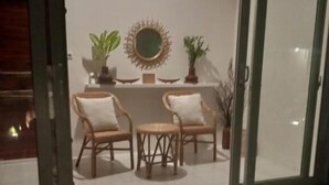 Een eetgedeelte met twee stoelen en een tafel, een spiegel en potplanten.