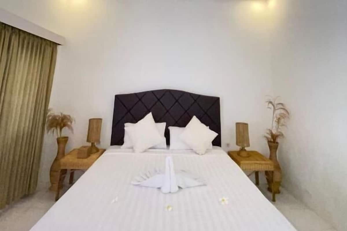 A hotel room with a large bed, two bedside tables, and a ceiling light.