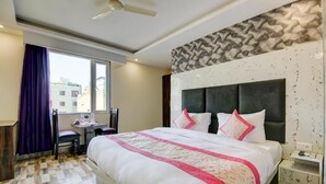 Une chambre d’hôtel avec un grand lit, un bureau et une fenêtre avec des rideaux.