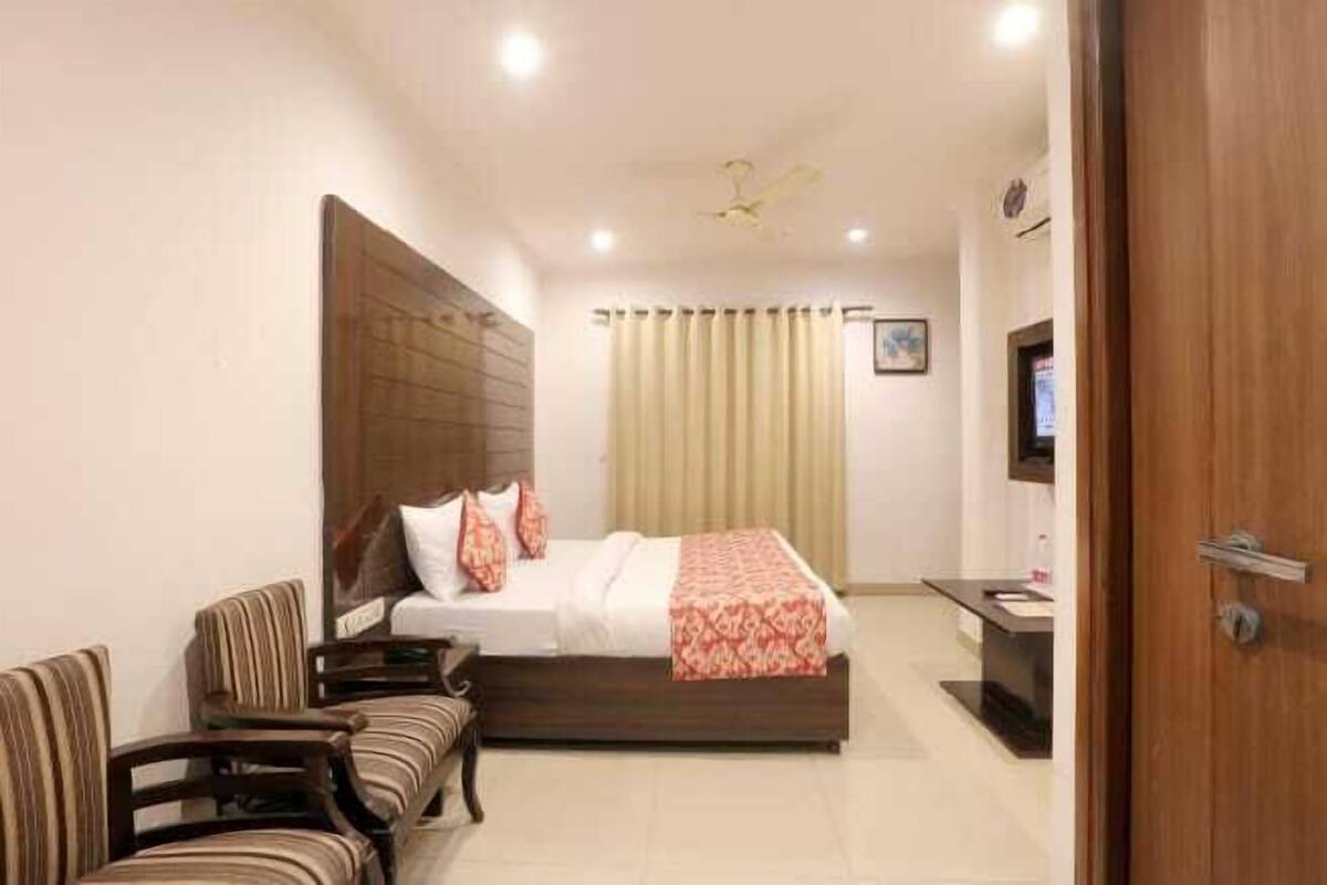 A hotel room with a bed, a desk, a chair, a television, and a ceiling fan.