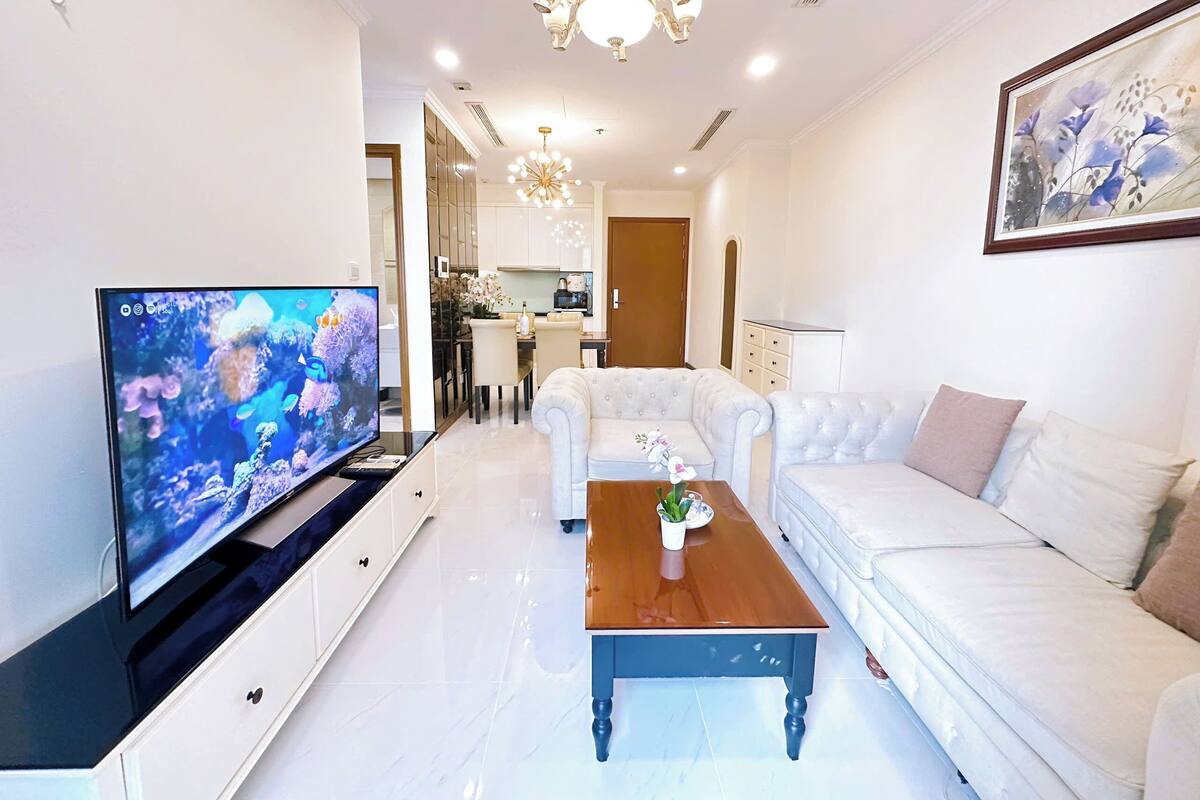 A modern living room with a flat-screen TV, a wooden coffee table, and a white sofa.