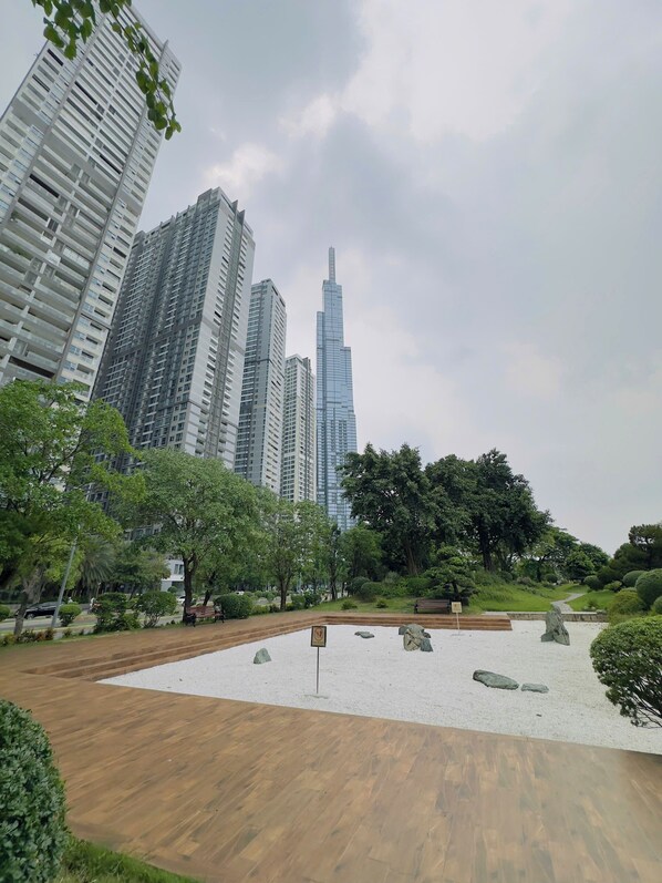 A park with a wooden deck, a white gravel area, and a large tree.