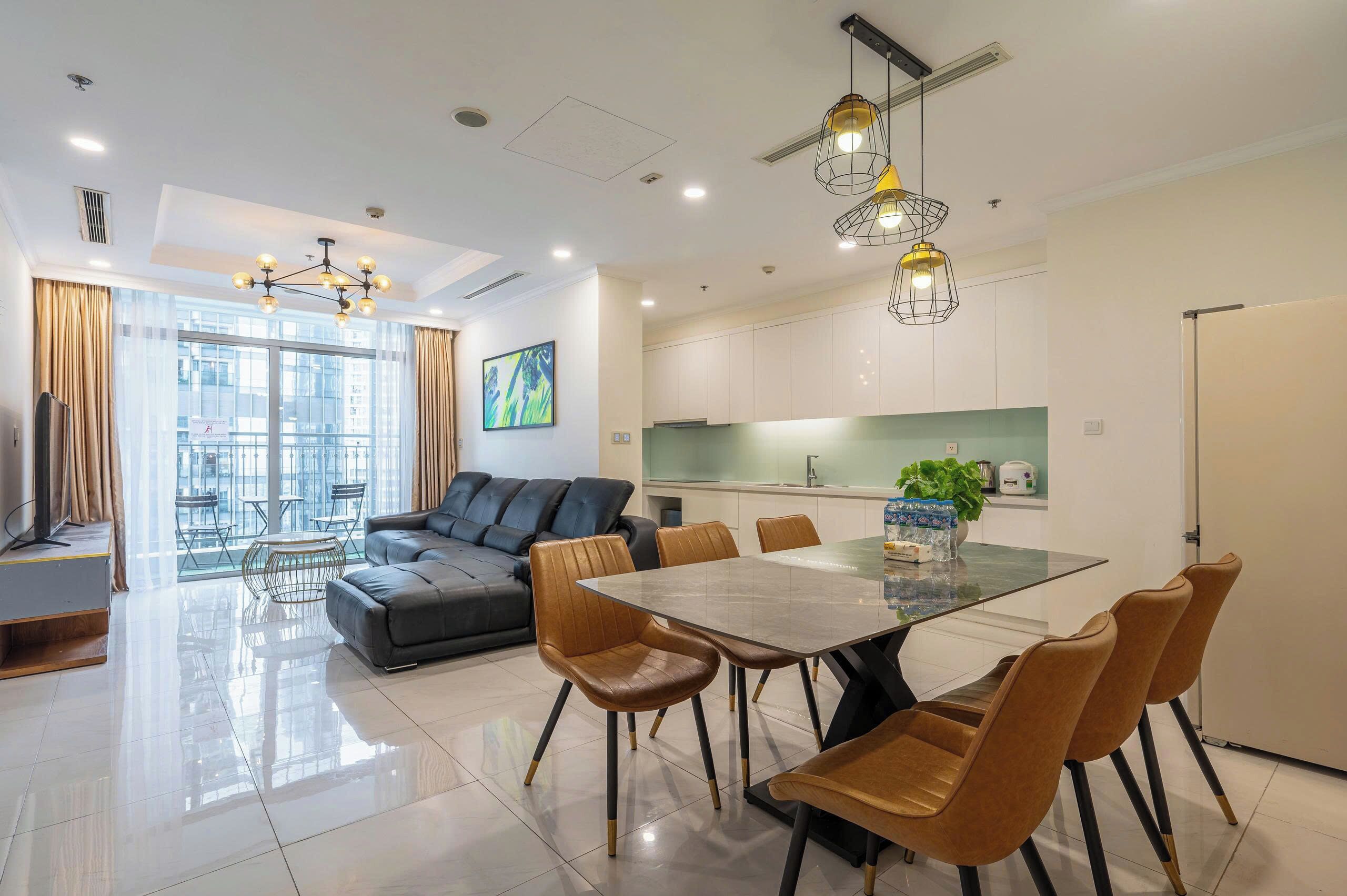 Uma sala de estar moderna com sofá, mesa de jantar, cadeiras e uma área de cozinha com armários e pia.